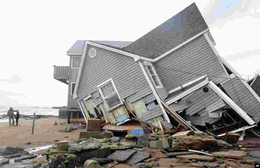 People stand next to a house collapsed from superstorm Sandy in East Haven, Conn. on Oct. 30, 2012.