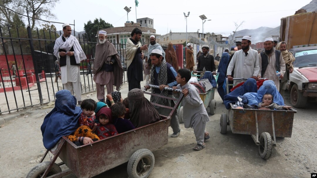 FILE - Afghan women and children sit in a cart pushed by a man as they enter Afghanistan through Pakistan's border crossing in Torkham, east of Kabul, Afghanistan, March. 11, 2015.