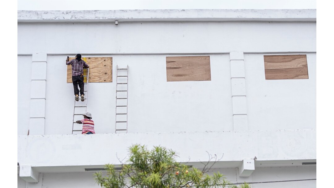 Trabajadores en Ciudad Belice protegen ventanas ante la llegada del huracán Nana el 2 de septiembre de 2020.