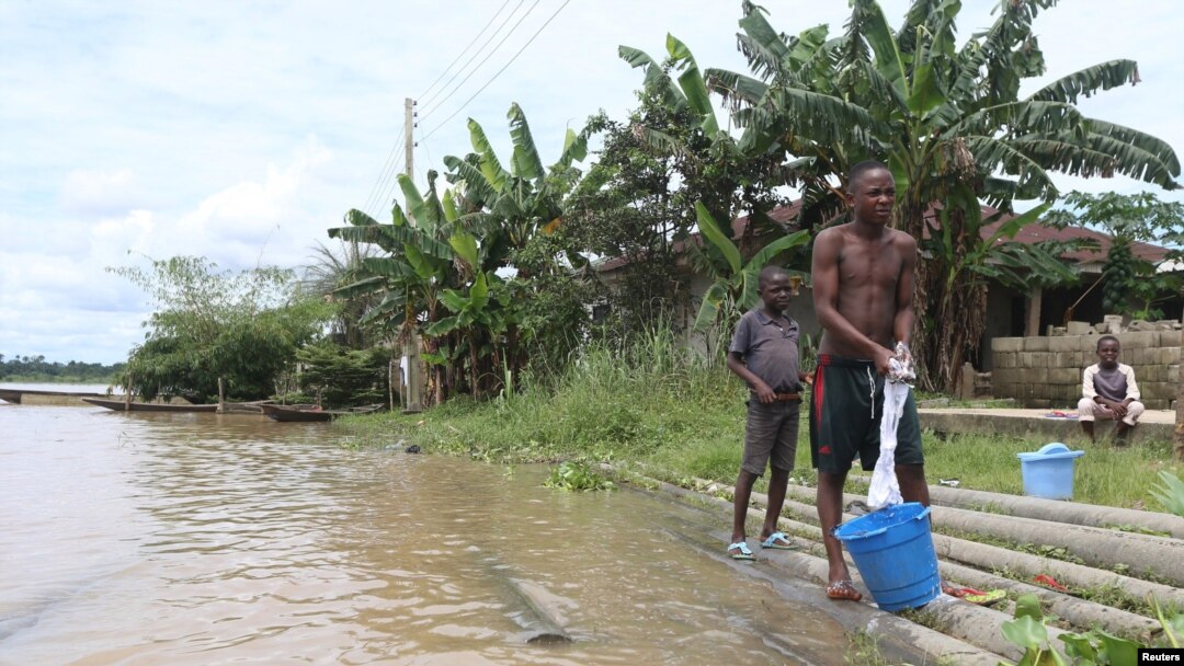 wadansu yara suna tsaye kusa da bututun mai da aka yi watsi da su.al, Yenagoa, babban birnin jihar Delta.