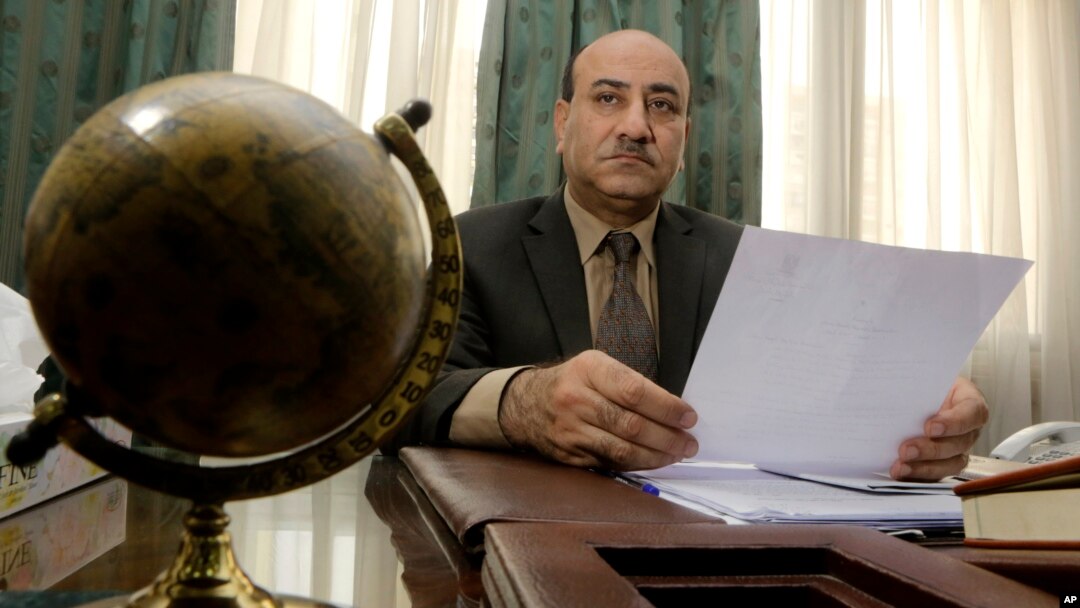 FILE - Hesham Genena, the head of Egypt's oversight body, holds documents at his office in Cairo, April 16, 2014.