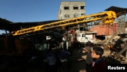 Palestinians inspect the scene of what witnesses said was an air strike on a workshop in Gaza City, May 5, 2016.