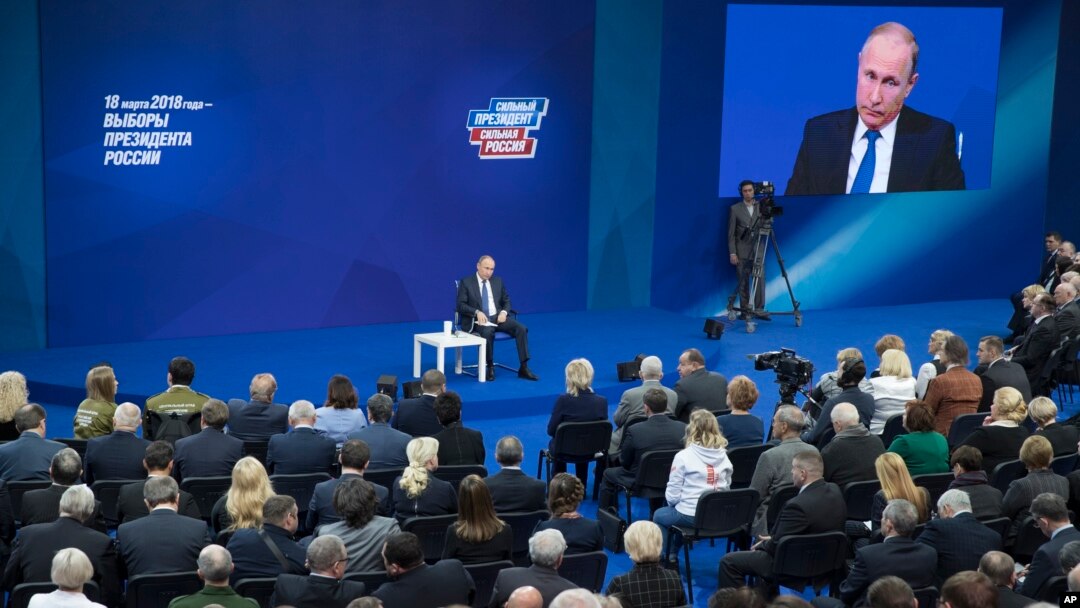 Russian President Vladimir Putin, sitting on the stage at centre rear, speaks to his supporters during a meeting for his campaign in Moscow, Jan. 30, 2018. 