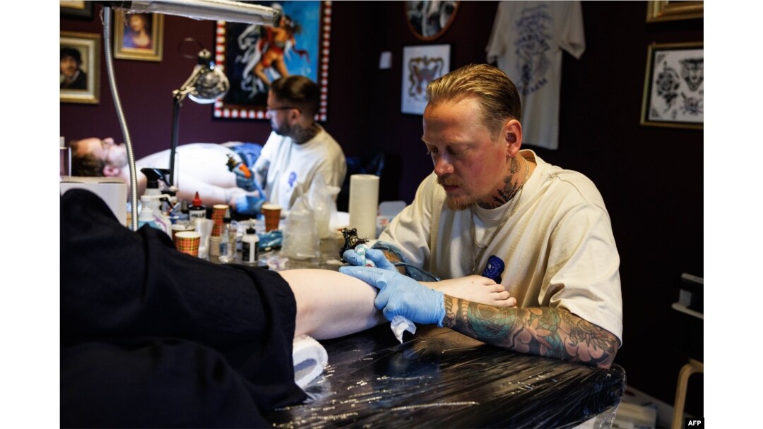 Tattoo artists ink designs on customers during a session at The Rembrandt House Museum in Amsterdam on June 19, 2023. (Photo by SIMON WOHLFAHRT / AFP)