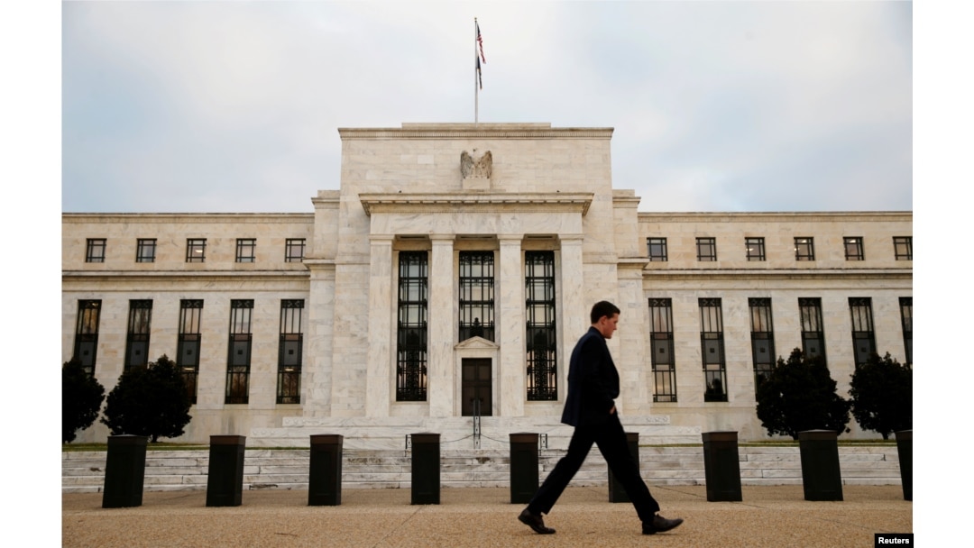 FILE - A man walks past the Federal Reserve Bank in Washington, D.C.