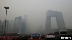 FILE - Cars travel on a road amid heavy haze in Beijing, Feb. 21, 2014. 