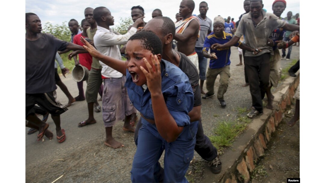 FILE - Protesters attack a policewoman in Bujumbura, Burundi, May 12, 2015, in a rally sparked by opposition to the president's decision to run for a third term.