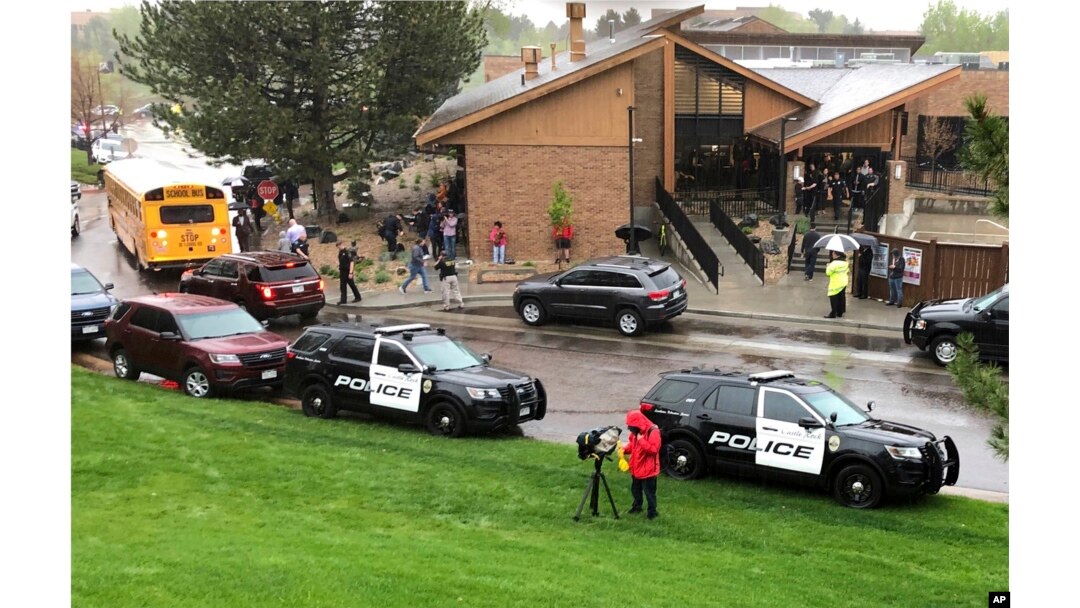 FILE - Police and others are seen outside a recreation center where students are reunited with their parents, in the Denver suburb of Highlands Ranch, Colo., after a shooting at STEM School Highlands Ranch, May 7, 2019.