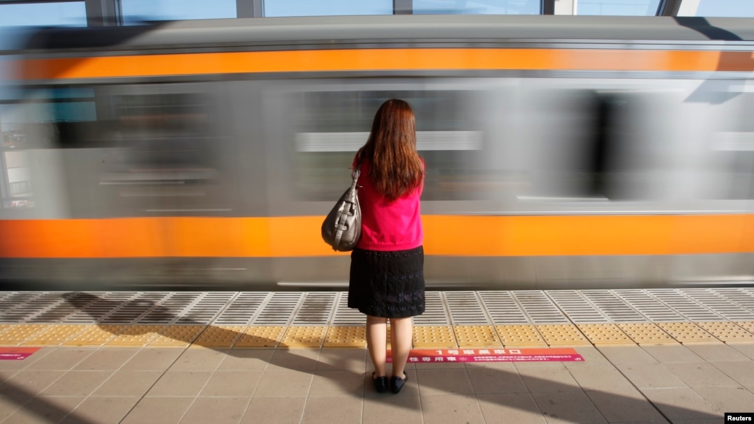 FILE - A woman waits to board a 'women only' passenger train during morning rush hours in Tokyo. The study examined responses from more than 9,600 women employees, submitted by mail or online.