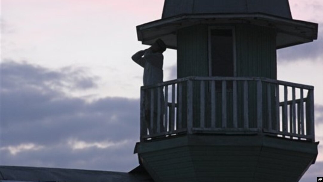 Member of Islamic sect calls for evening prayer from atop the house where followers lived in seclusion, Kazan, Russia, Aug. 9, 2012.