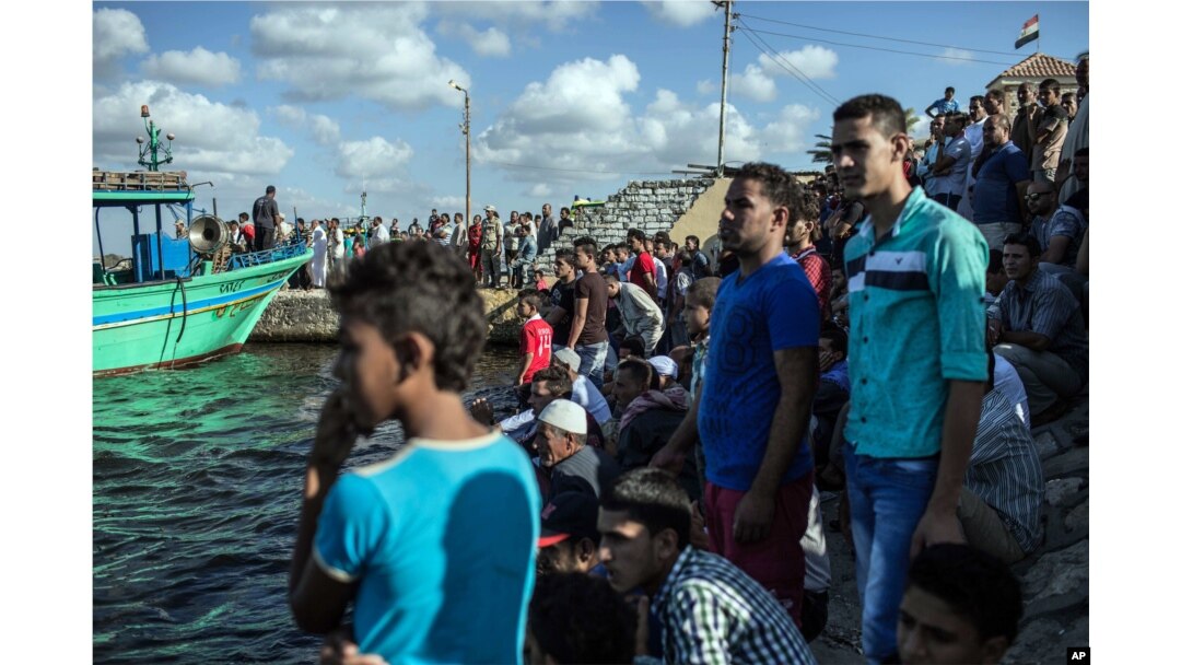 Egyptians wait on shore as a coast guard boat arrives carrying the bodies of migrants from a Europe-bound boat that capsized off Egypt’s Mediterranean coast, in Rosetta, Egypt, Sept. 22, 2016.