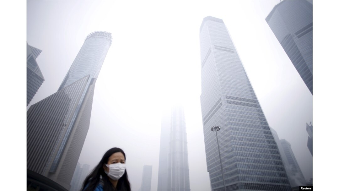 FILE - A woman wearing a mask walks past skyscrapers amid heavy smog in Shanghai, China, Dec. 11, 2015. United Nations Secretary-General Ban Ki-moon said that acting on climate change promises "new markets," along with "better jobs" and "better health."