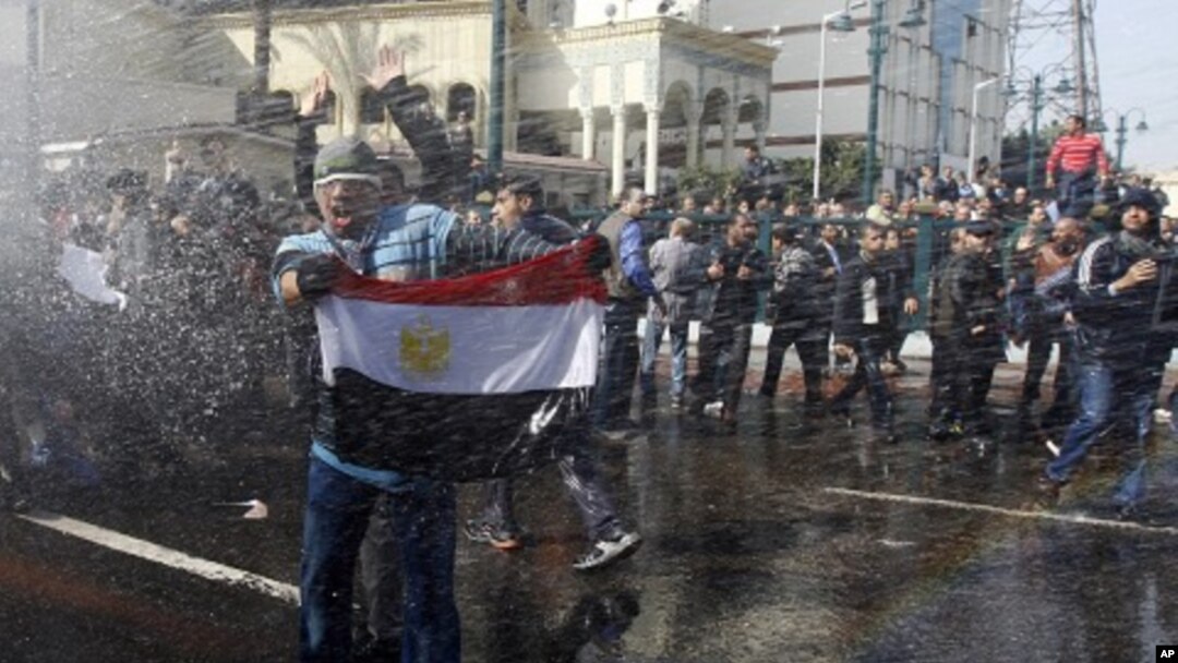 A protester holds an Egyptian flag as he stands in front of water canons during clashes in Cairo, Jan 28, 2011