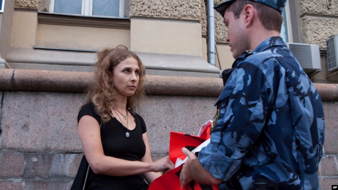 Russian activist of the feminist protest group Pussy Riot Maria Alekhina talks to a policeman as she holds a protest in front of the Federal Penitentiary building in Moscow, Russia, Aug. 7, 2018. 
