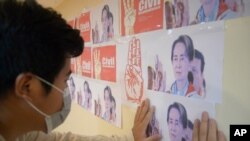 Un manifestante antigolpista observa las imágenes de la derrocada líder birmana Aung San Suu Kyi, durante una protesta contra el golpe militar en Rangún, Myanmar, el lunes 26 de abril de 2021.