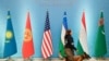 FILE - A security officer with a sniffer dog passes national flags, from left, Kazakh, Kyrgyz, U.S., Uzbek, Tajik and Turkmen, before leaders gather for a group picture during a meeting of the C5+1 in Tashkent, Uzbekistan, Feb. 3, 2020.
