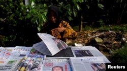 FILE - A newspaper seller prepares her stall with articles dominated by the election of U.S. Republican Donald Trump, in Jakarta, Indonesia, Nov. 10, 2016. 