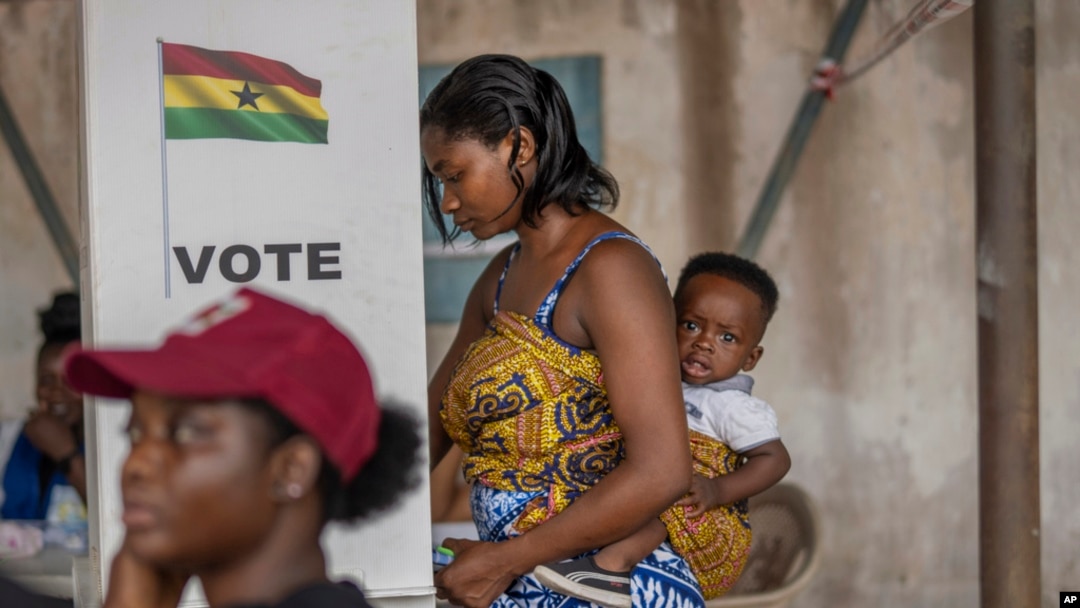 A woman with her child prepares her ballot in the general elections in Accra, Ghana, Dec. 7, 2024.
