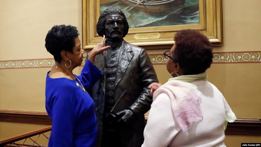 Joyce Amos, left, and Pamela Johnson, who both work in the office of Maryland House Speaker Adrienne Jones, inspect a bronze statue of abolitionist Frederick Douglass during a private viewing ahead of its unveiling at the Maryland State House, Monday, Feb