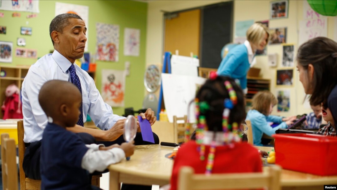 U.S. President Barack Obama reads a card during a game with children in a per-kindergarten classroom at College Heights early childhood learning center in Decatur, Georgia, February 14, 2013. 