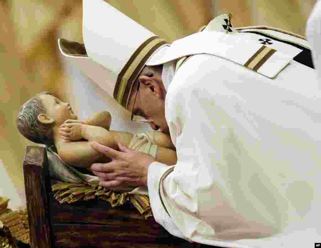 Pope Francis kisses a statue of Baby Jesus as he celebrates the Christmas Eve Mass in St. Peter's Basilica at the Vatican, Dec. 24, 2014.