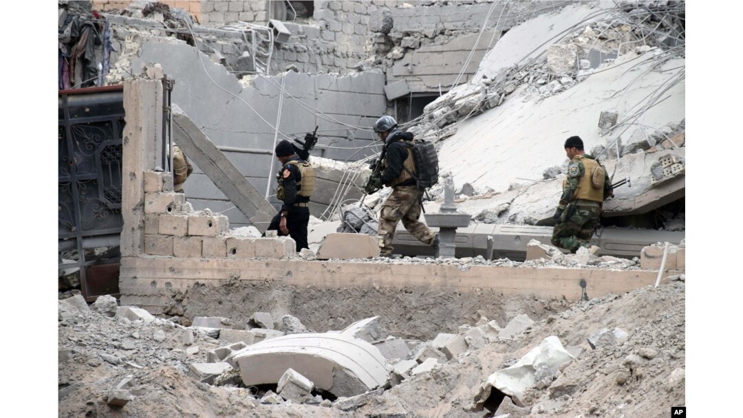 FILE - Iraqi security forces, supported by U.S.-led coalition airstrikes, advance their position through damaged buildings toward central Ramadi, Dec. 24, 2015. Rebuilding is crucial to keep control of the city.