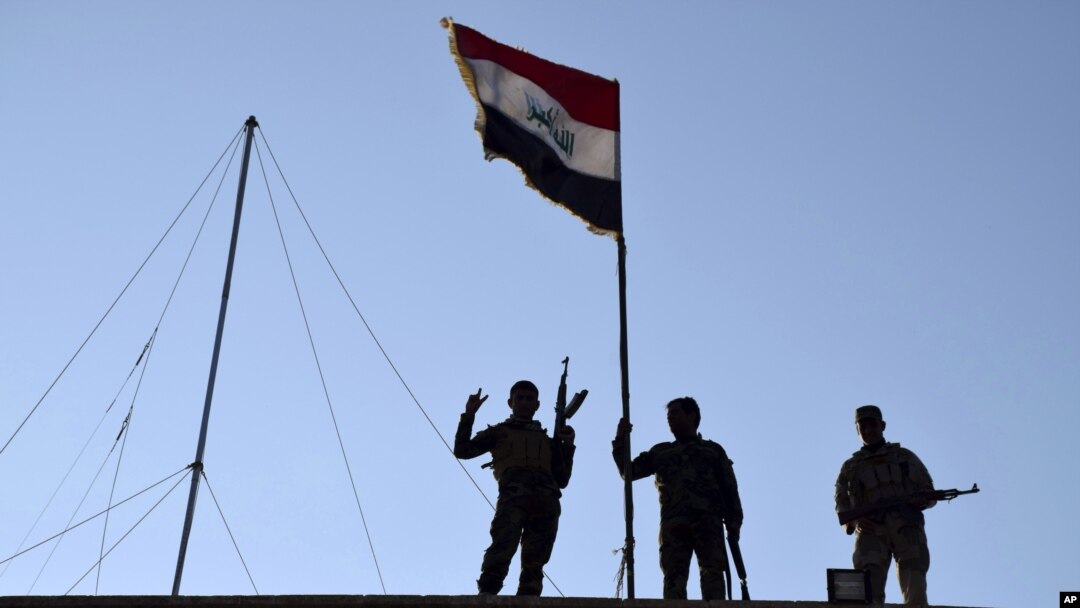 FILE - Iraqi soldiers plant the national flag over a government building in Ramadi, Dec. 21, 2015.