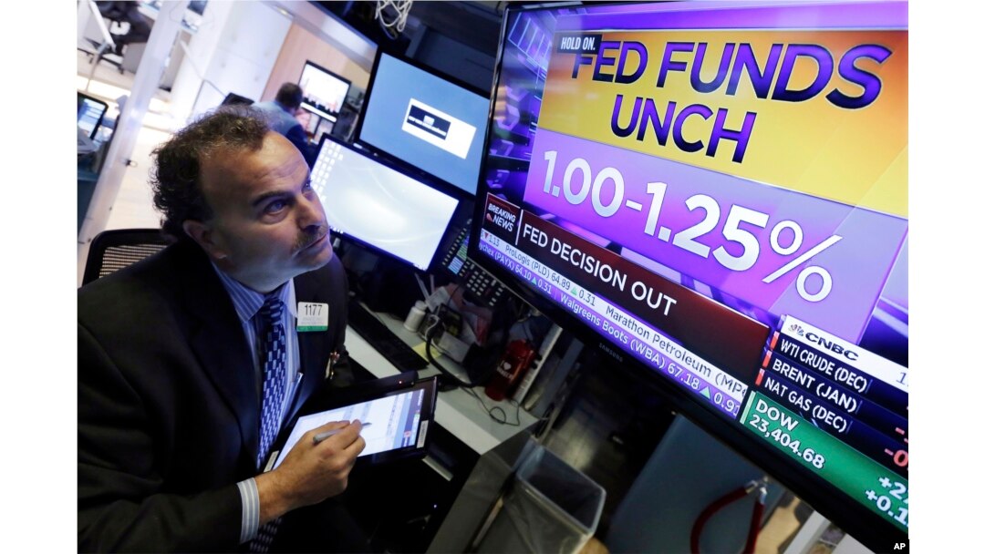 Trader Gerard Farco watches a television on the floor of the New York Stock Exchange showing the rate decision of the Federal Reserve, Nov. 1, 2017. With a new Federal Reserve leader announced, the Fed is keeping its key interest rate unchanged.