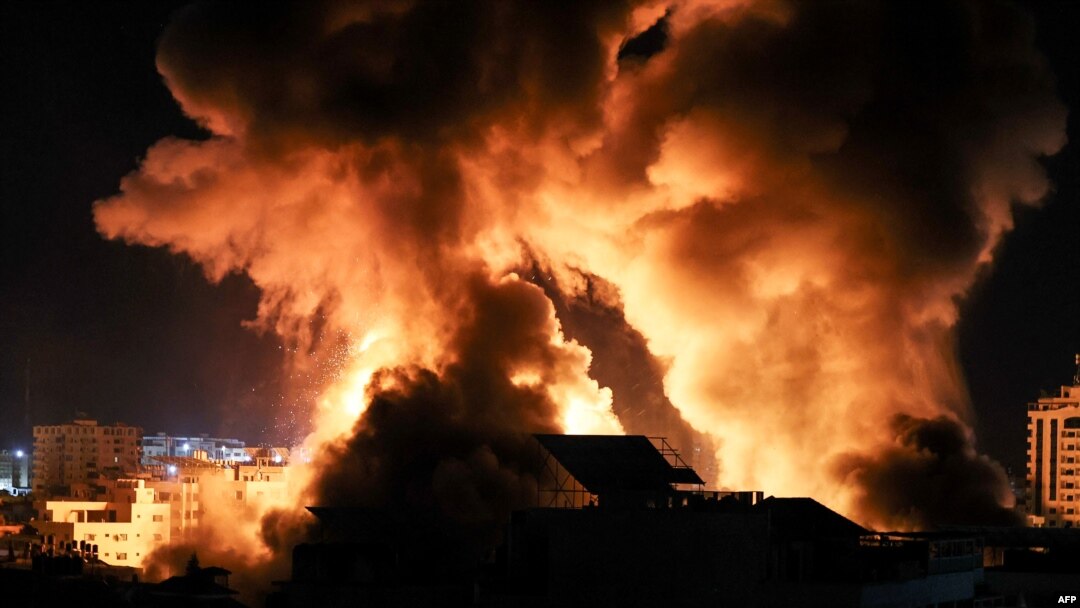 The sky is lit by an explosion above buildings in Gaza City as Israeli forces shell the Palestinian enclave, early May 18, 2021.