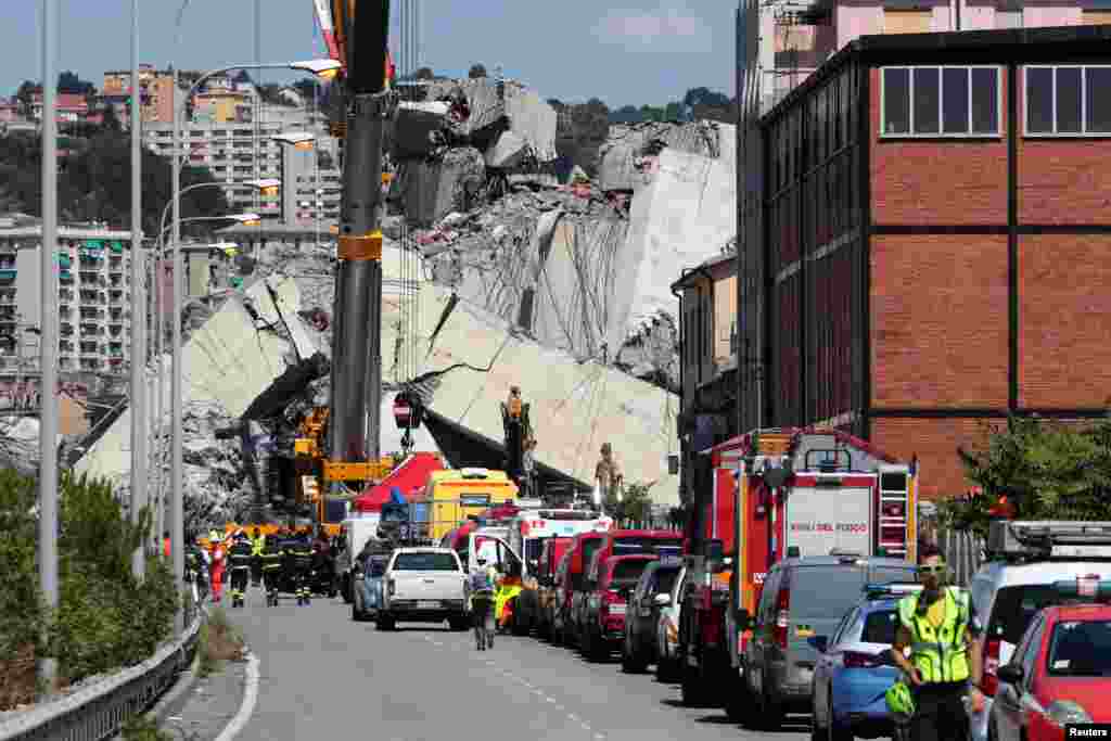 Firefighters and rescue workers stand at the site of a collapsed Morandi Bridge in the port city of Genoa, Italy. Rescuers searched for survivors among towering slabs of concrete wreckage after the bridge collapse killed 39 people and sparked a furious government reaction against the viaduct’s operator.