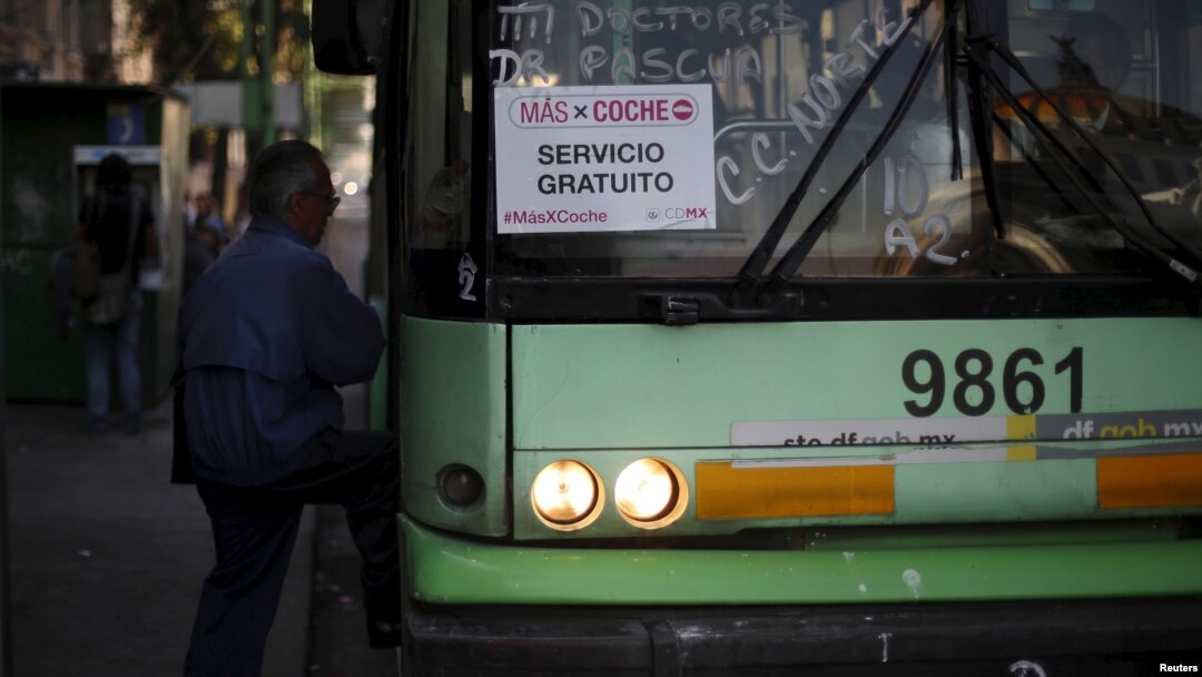 A passenger boards an electric bus displaying a sign that reads "MasXCoche. Free Service" in Mexico City, Mexico, April 5, 2016. 