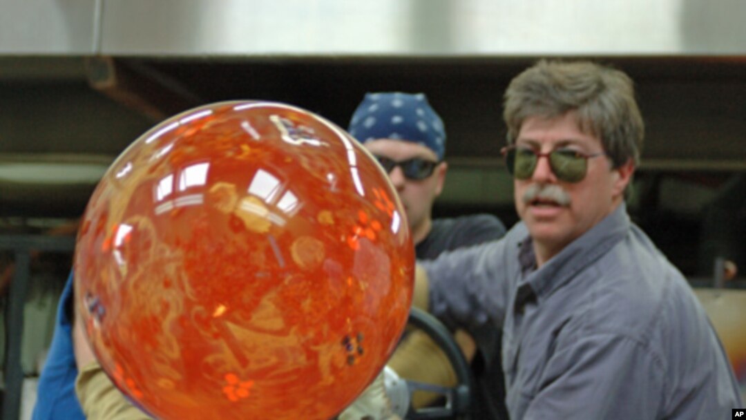 Glass artist Josh Simpson turns one of his signature planet-like spheres after heating it in a furnace. 