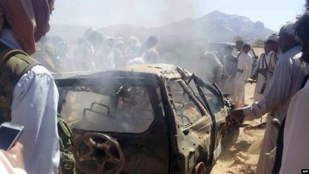 Yemenis gather around a burned car after it was targeted by a drone strike, which killed three suspected al-Qaida militants, between Marib and Chabwa provinces, a desert area east of Sana'a, Jan. 26, 2015.