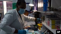 Técnicos de laboratorio analizan una muestra de sangre para detectar infección por VIH en el Instituto de Salud Reproductiva y VIH (RHI) en Johannesburgo, el jueves 26 de noviembre de 2020.