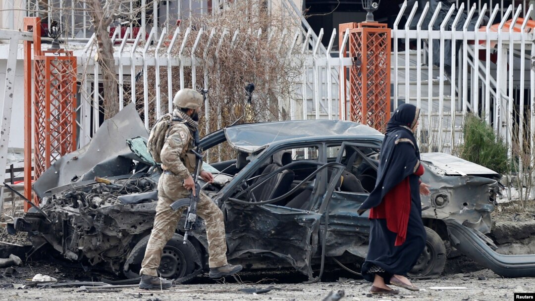 FILE - A member of Afghan security forces inspects a damaged vehicle at the site of a blast in Kabul, Afghanistan, Dec. 20, 2020. 