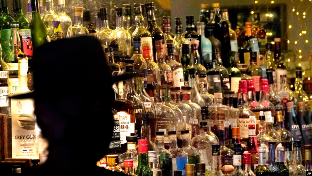 FILE - Bottles of alcohol sit on shelves at a bar in Houston, June 23, 2020. 