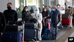 Los pasajeros que hacen fila para un vuelo humanitario a Italia usan equipo de protección en medio de la nueva pandemia de coronavirus que ha cancelado vuelos nacionales e internacionales, en el aeropuerto El Dorado en Bogotá, Colombia, en mayo.