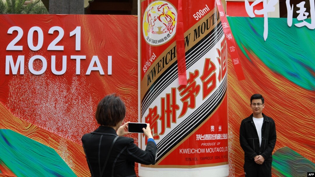 FILE - People take photos outside the stand for Kweichow Moutai, a Chinese liquor brand, at the China Food and Drinks fair in Chengdu, in China's southwest Sichuan province, April 4, 2021.
