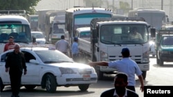 A worker directs vehicles queuing in line at a petrol station, Cairo, March 12, 2013.