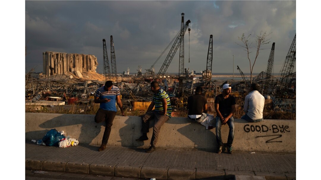 People sit near the site of last week's explosion that hit the seaport of Beirut, Lebanon, Aug. 11, 2020.