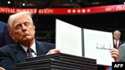 特朗普手持剛簽署的行政命令，兌現競選承諾。民調顯示，驅逐犯罪移民的政策最受美國人民歡迎。 (法新社：2025年1月20日)