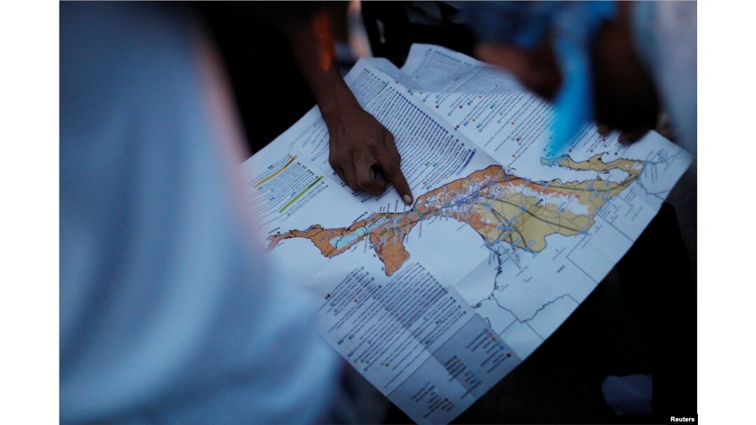 FILE - A migrant, part of a caravan of thousands traveling from Central America en route to the United States, points at a map while rest in Santiago Niltepec, Mexico, Oct. 29, 2018.