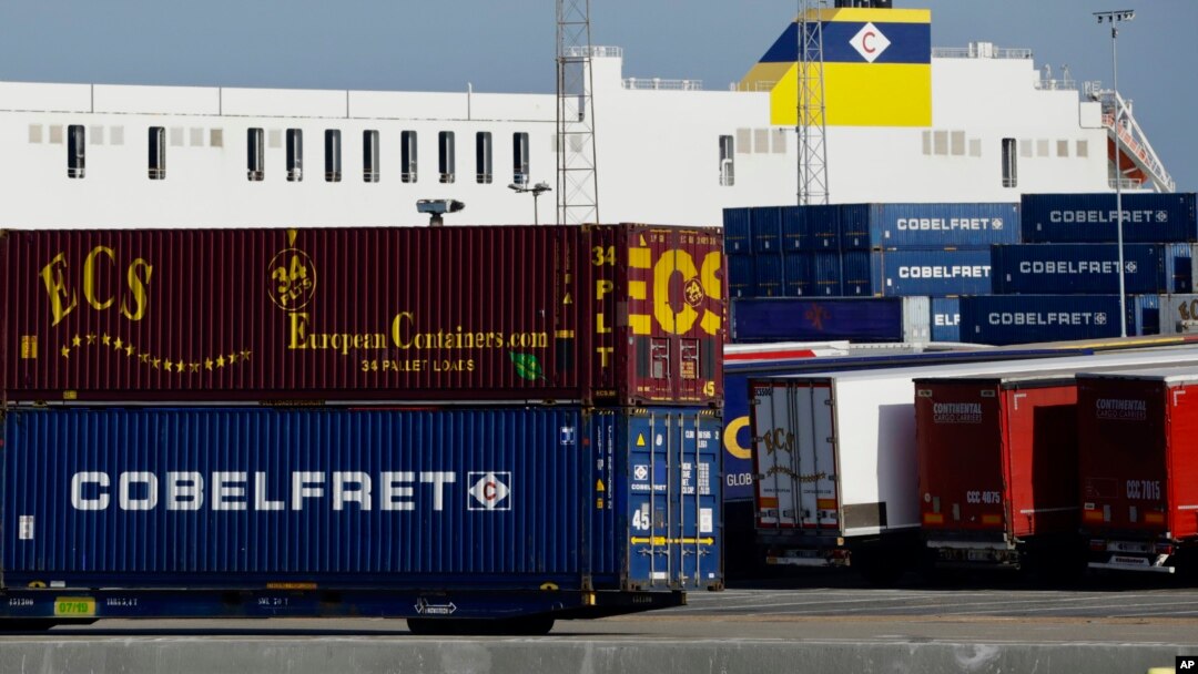Truck trailers are parked among stacked cargo containers at the Port of Zeebrugge, in Zeebrugge, Belgium, Oct. 24, 2019.
