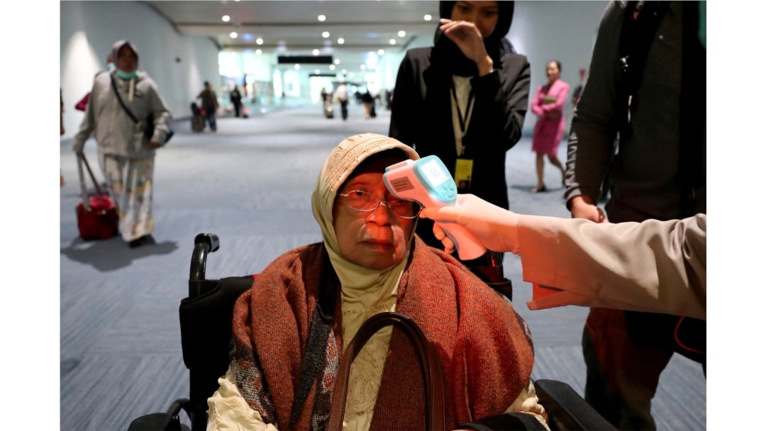 A health official scans the body temperature of a passenger as she arrives at the Soekarno-Hatta International Airport in Tangerang, Indonesia, Wednesday, Jan. 22, 2020. (AP Photo/Tatan Syuflana)