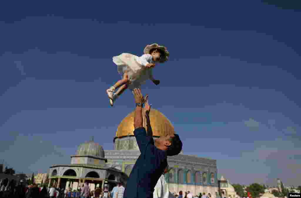 A Palestinian man throws his child in the air following morning prayers marking the first day of Eid al-Adha celebrations, on the compound known to Muslims as al-Haram al-Sharif and to Jews as Temple Mount in Jerusalem's Old City.