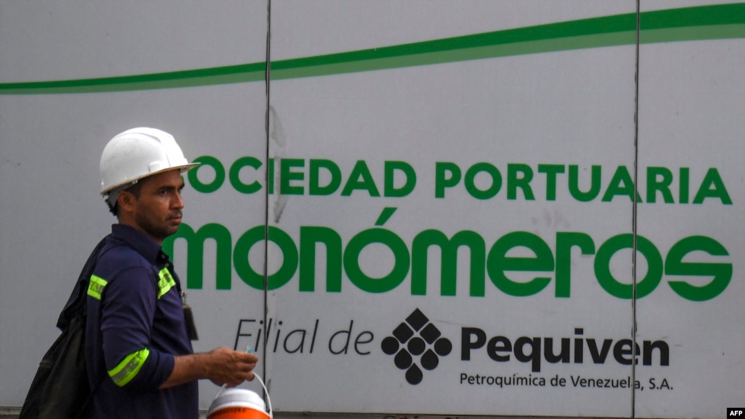 ARCHIVO - Un trabajador camina junto a un cartel de la empresa venezolana de fertilizantes Monómeros, en Barranquilla, Colombia, el 9 de octubre de 2021.