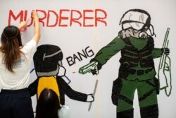 一名香港反送中抗议者在手绘一幅全副武装的蒙面港警开枪实弹射击一名抗议学生情景的壁画。（2019年10月2日）