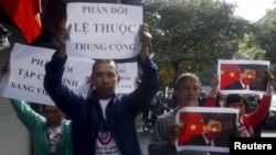 FILE - Protesters hold marked images of Chinese President Xi Jinping and anti-China signs during a protest ahead of his visit to Vietnam, on the street in Hanoi, Nov. 3, 2015.