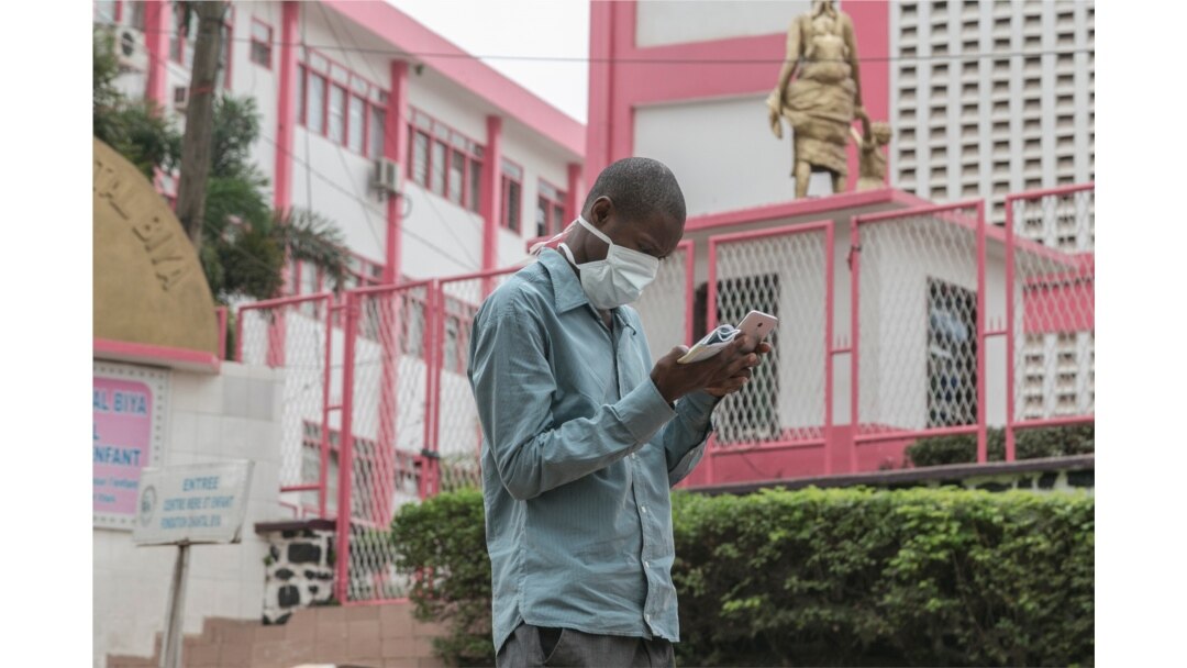 FILE - A man wears a mask while walking outside the entrance to the Yaounde General Hospital in Yaounde, March 6, 2020.