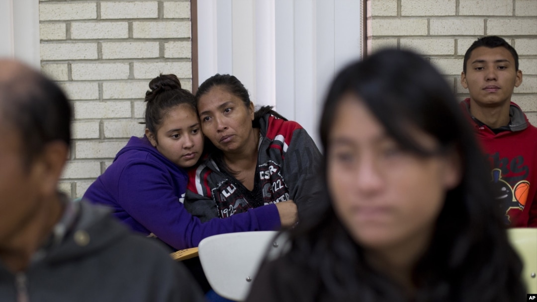 FILE - Central American migrants embrace as they wait for assistance at a center for newly-arrived migrant families with children, at Sacred Heart Catholic Church in McAllen, Texas. Assistance includes clothes, a meal, a shower and access to medical care, Jan. 5, 2016.